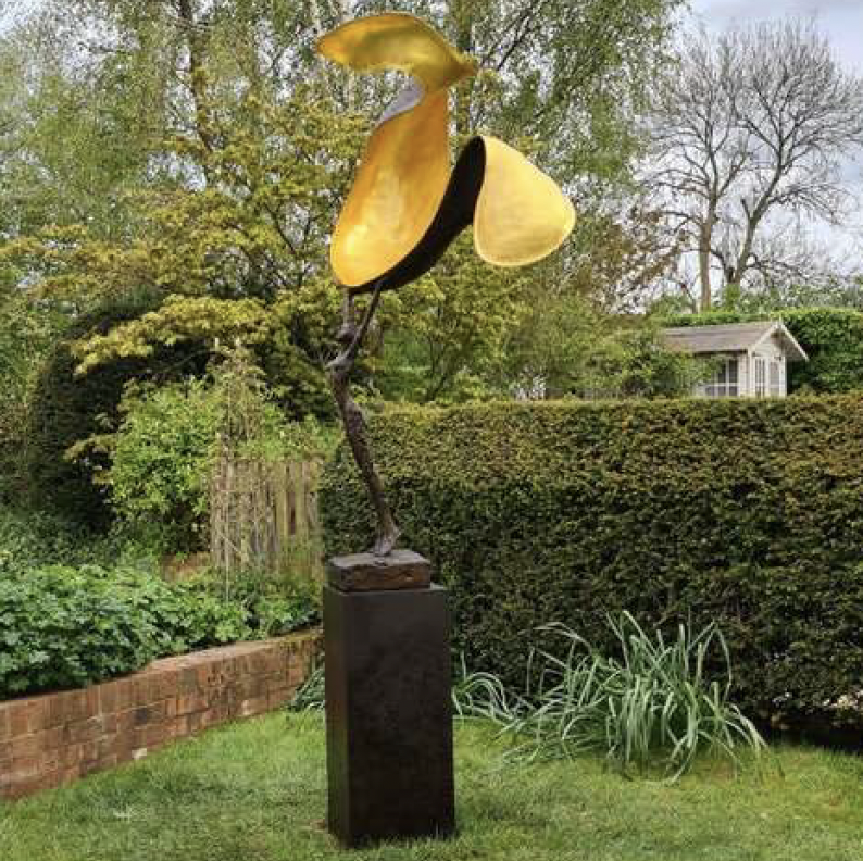 Red Scarf sculpture on a rusted steel plinth in a garden.